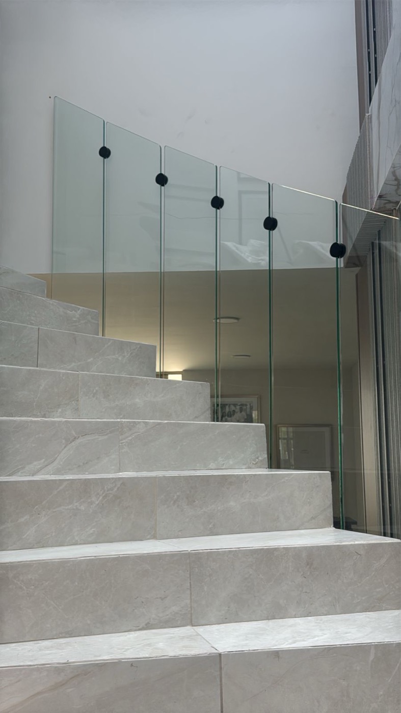 Barandal de vidrio templado minimalista sobre escalera de mármol en Querétaro