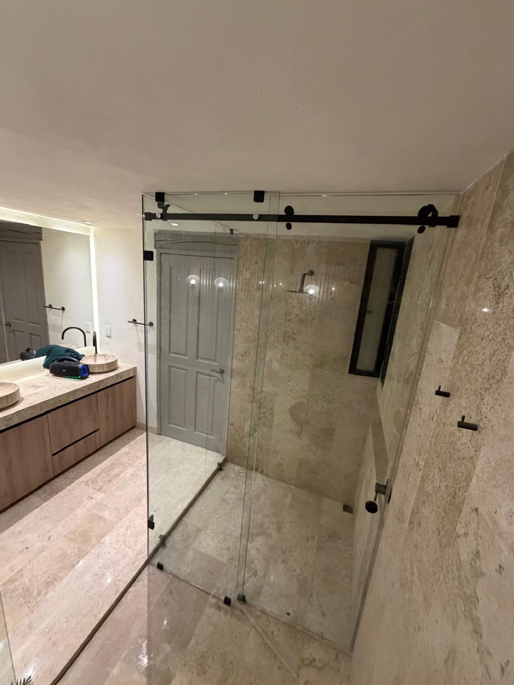 Cancel de baño tipo granero sobre baño de mármol en Querétaro
