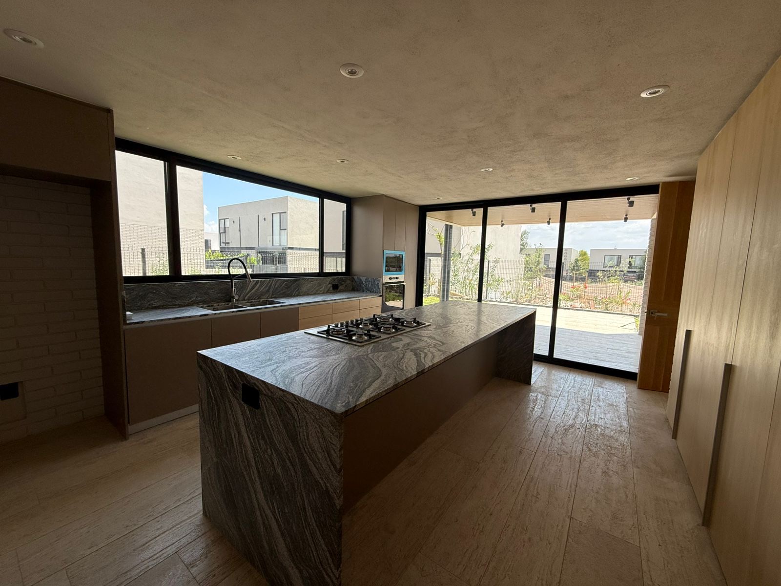 Cocina con isla de mármol y muro de vidrio hacia la terraza