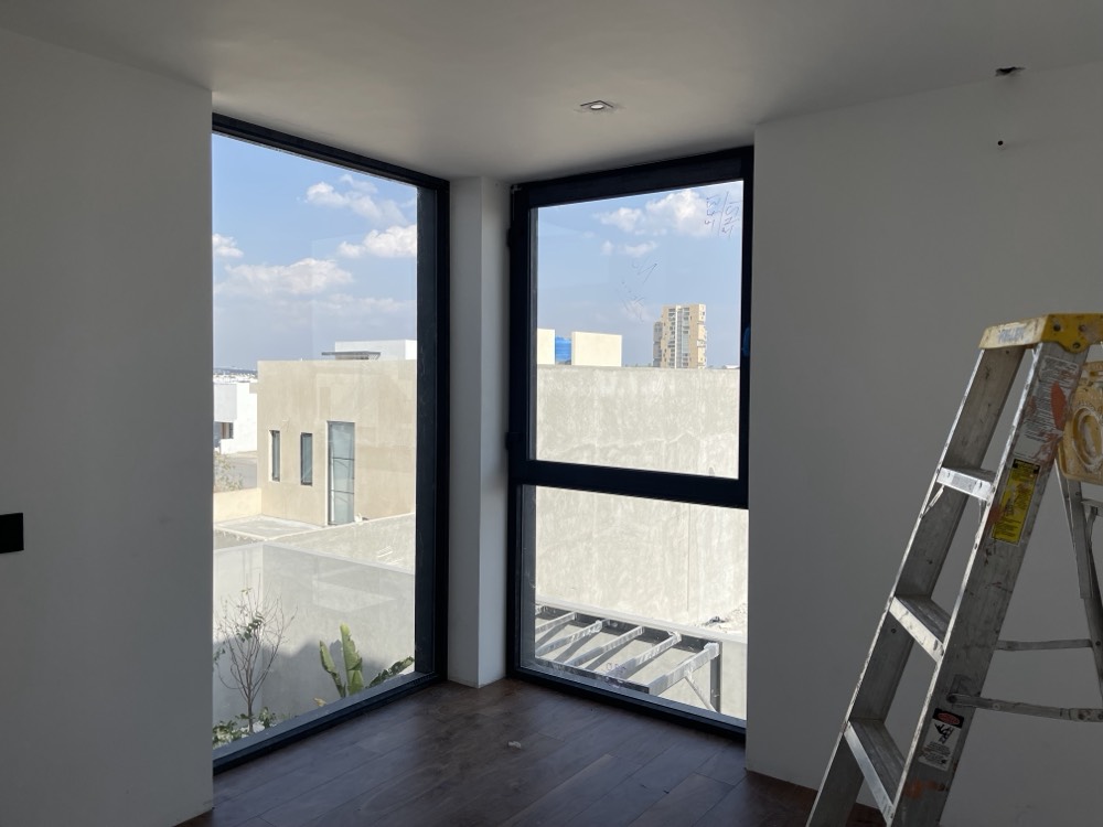 Ventanas de esquina con perfil oscuro en vivienda en obra