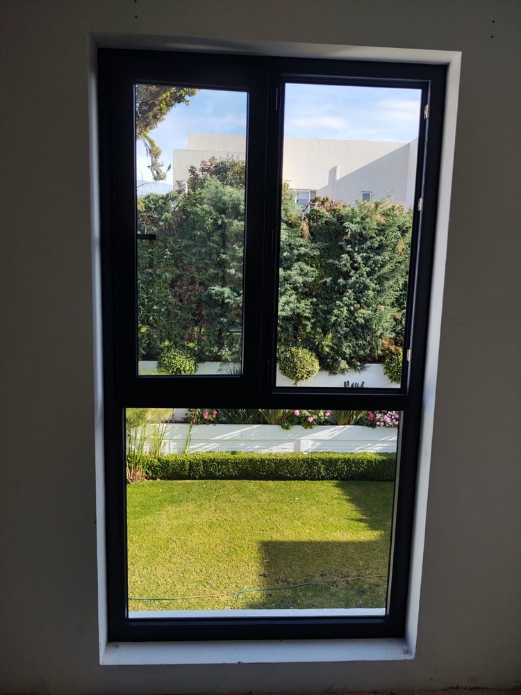 Ventana abatible con fijo inferior y vista al jardín
