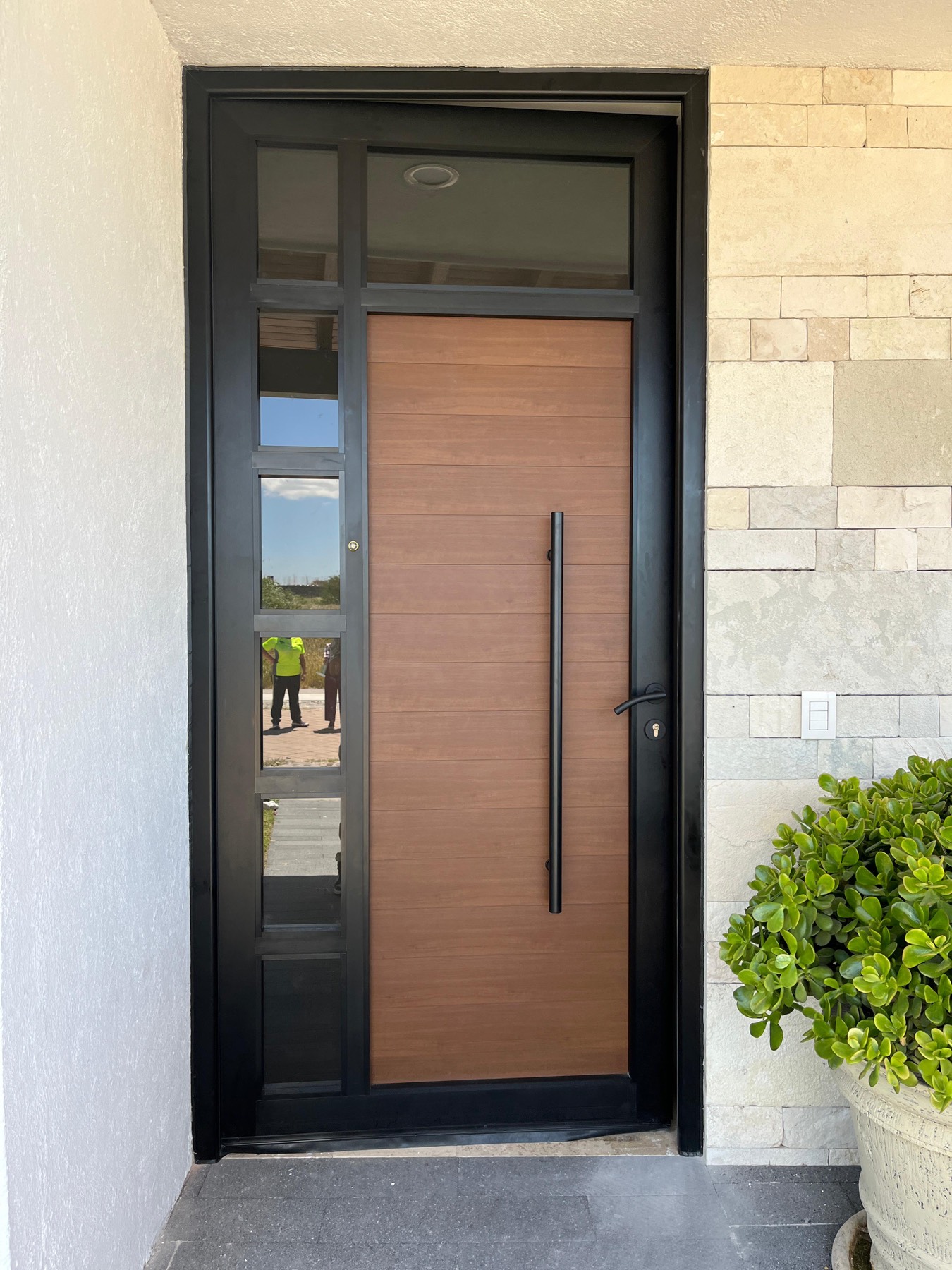 Puerta principal de aluminio con acabado imitación madera en una residencia de Querétaro
